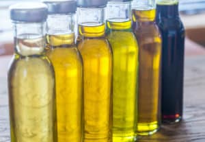A variety of cooking oils in clear bottles on a counter