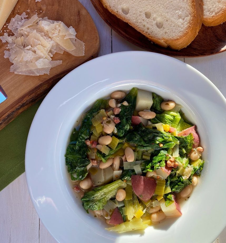 A bowl of beans and greens with Italian bread and Parmesan Cheese
