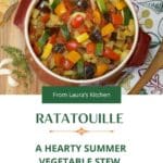 A large round casserole filled with ratatouille with a piece of French bread in the background.
