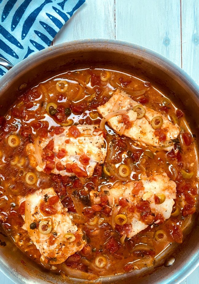 A saute pan with 4 cod fillets in a tomato veracruz sauce