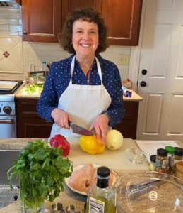 A person standing in the kitchen cutting a bell pepper
