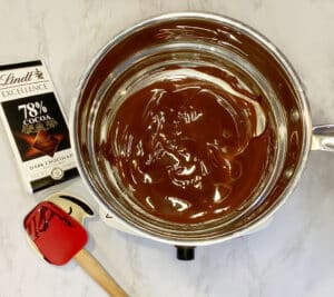 Melted dark chocolate in the top of a double boiler on a white counter top