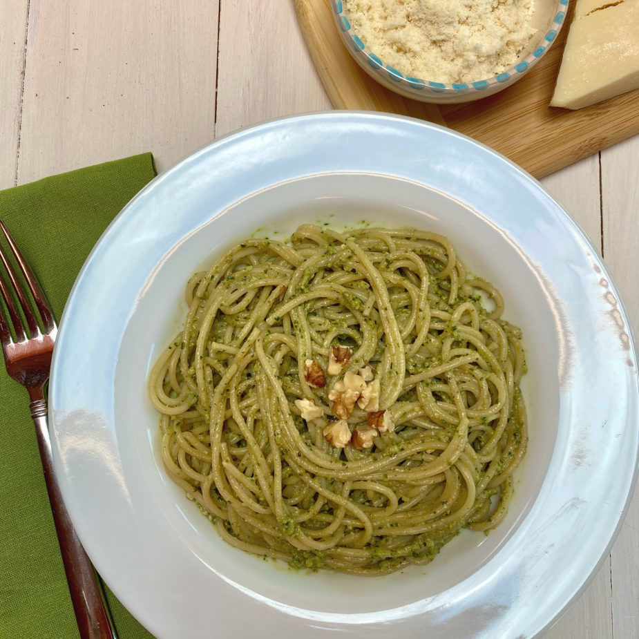 A white bowl filled with walnut arugula pesto tossed with pasta tossed in a pesto sauce