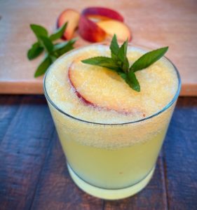 A glass with peach puree and ginger simple syrup topped with seltzer water.