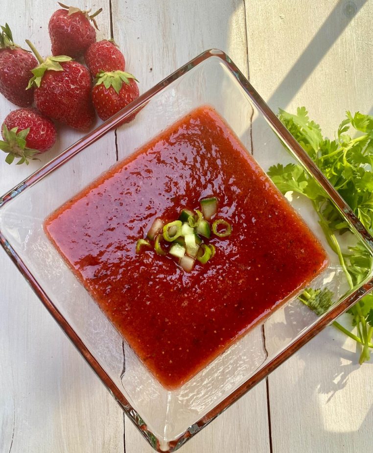 A glass bowl of strawberry gazpacho soup