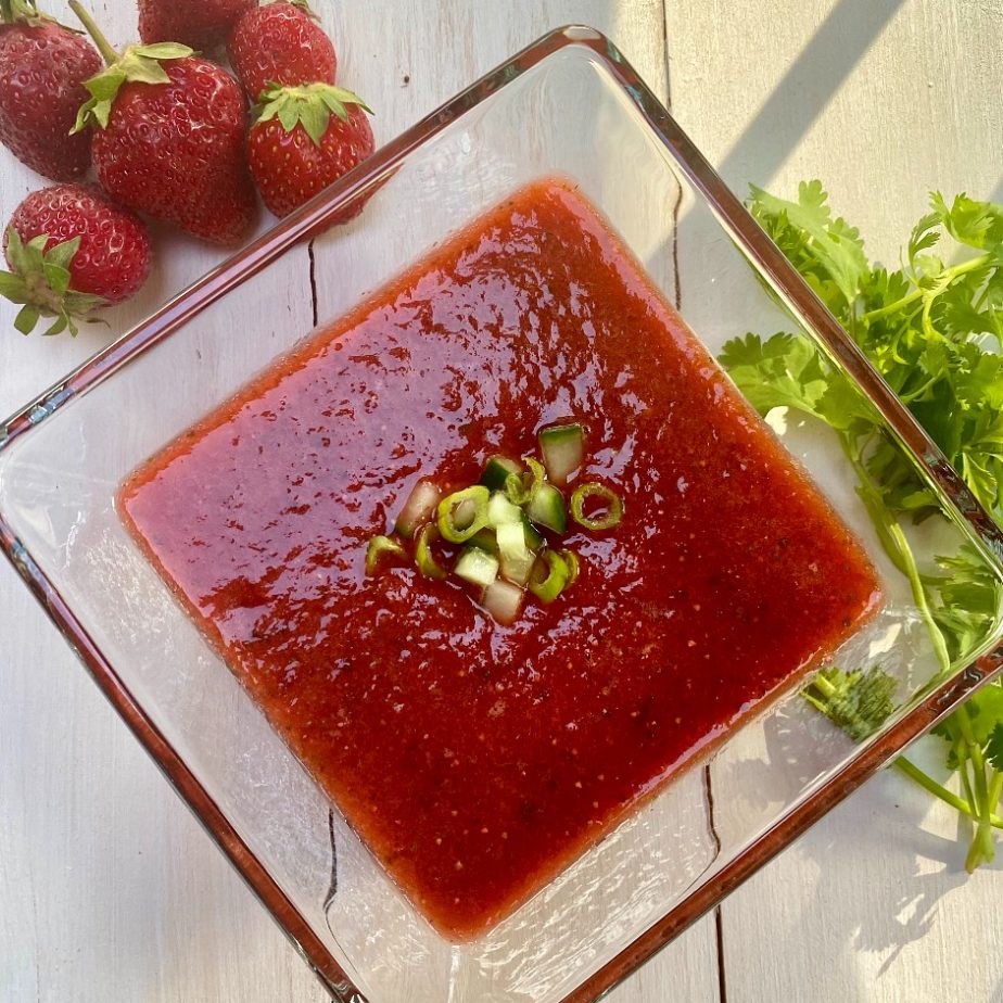 A glass bowl of strawberry gazpacho soup