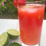 A glass of pink watermelon and lime with sparkling water on a picnic table