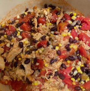 Cooking chicken, tomatoes, black beans and corn in a stock pot for soup.