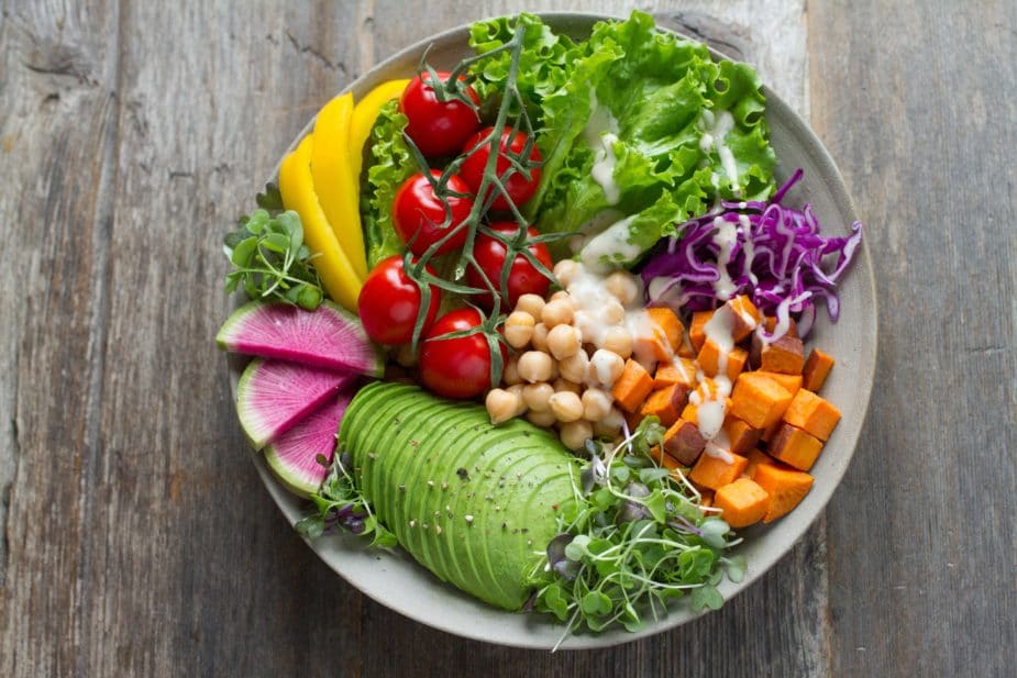 A plate full of colorful fruits and vegegtables on a wood board