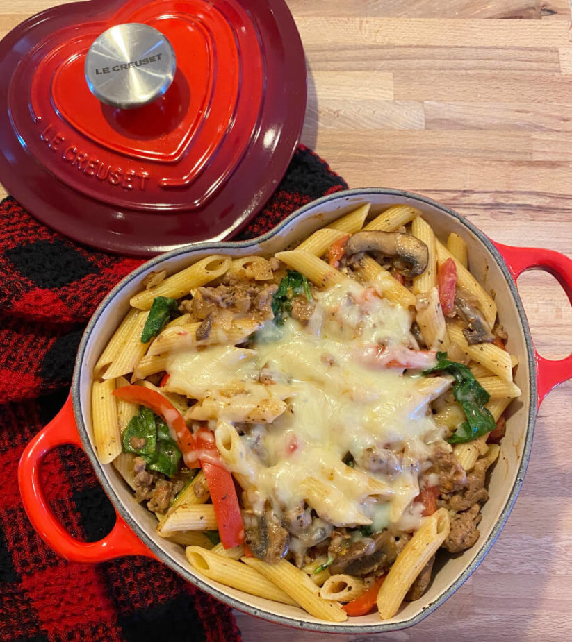 A heart shaped dish with a penne pasta and tomato casserole