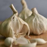 A wooden cutting board with garlic bulbs and cloves