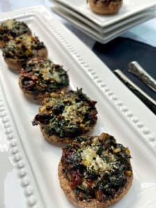 A white platter of spinach stuffed mushrooms