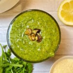 A bowl of arugula pesto on a white background