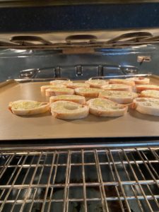 Crostini on a baking sheet placed about 3 inches below the boiler