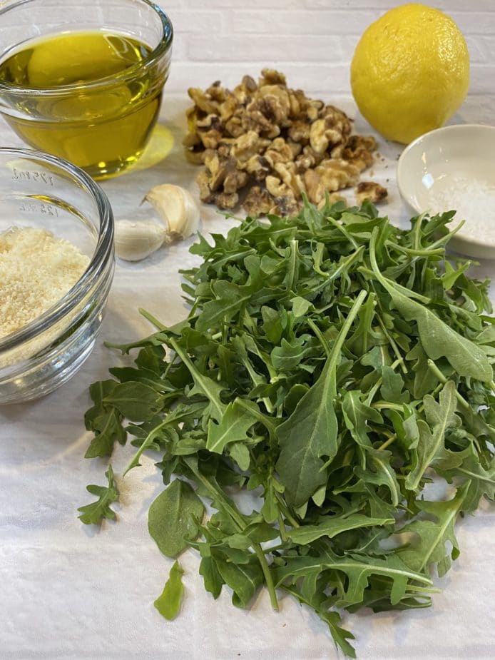 Arugula, Parmesan cheese, walnuts, olive oil, lemon and garlic on a white board