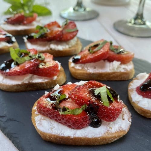 A tray of strawberry crostini with goat cheese and a balsamic glaze