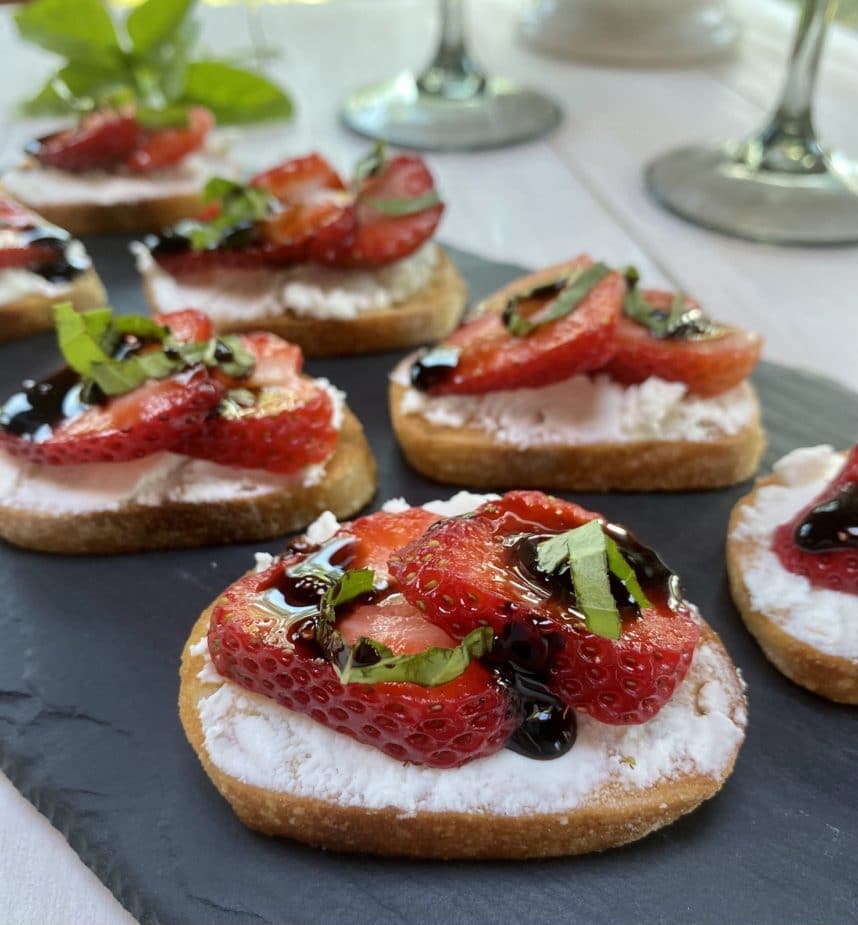 A tray of strawberry crostini with goat cheese and a balsamic glaze