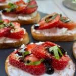 A tray of strawberry crostini with goat cheese and a balsamic glaze