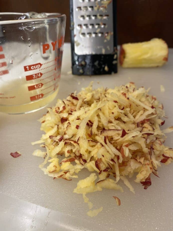 Shredded apple on a cutting board that has been squeezed dry.