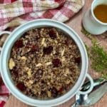 A white bowl filled with a quinoa salad with fresh cherries and toasted almonds. Citrus vinaigrette is on the side