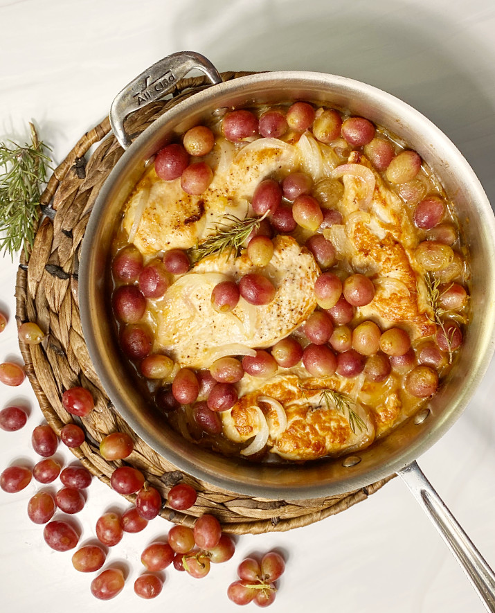 A saute pan with chicken and roasted grapes and rosemary