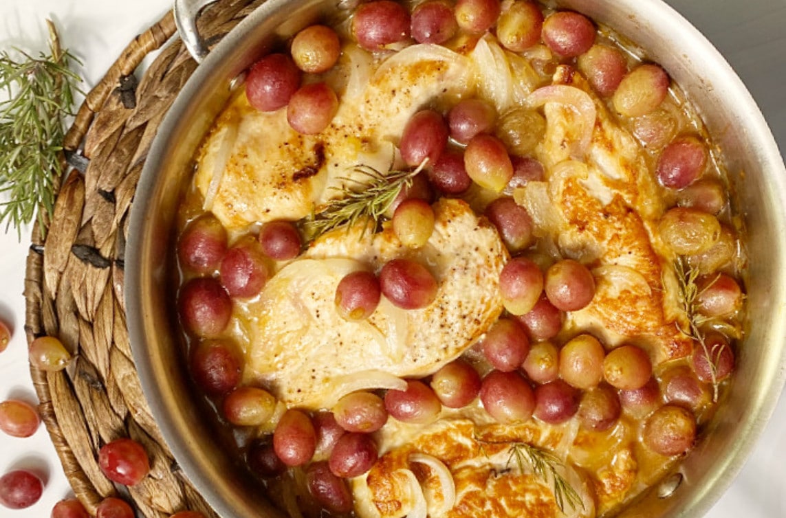 A sautepan with chicken breasts and roasted grapes