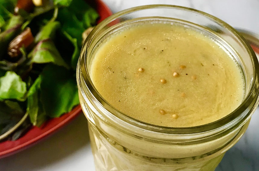 Honey Dijon Dressing in a Mason Jar next to a salad