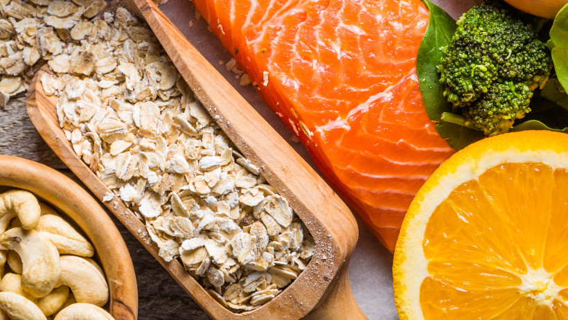A board with nuts, oatmeal, salmon and green vegetables