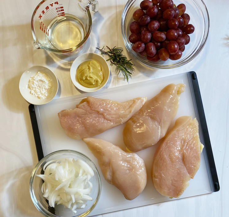 Ingredients on a white table that are needed to make chicken with roasted grapes recipe