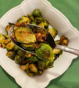 A serving spoon full of Roasted Brussel sprouts over a bowl