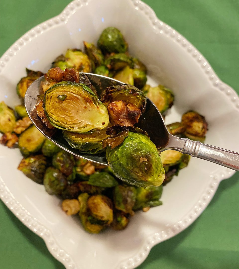 A serving spoon full of Roasted Brussel sprouts over a bowl