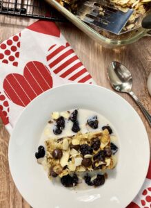 A white bowl with a slice of dark chocolate chip baked oatmeal with dried cherries