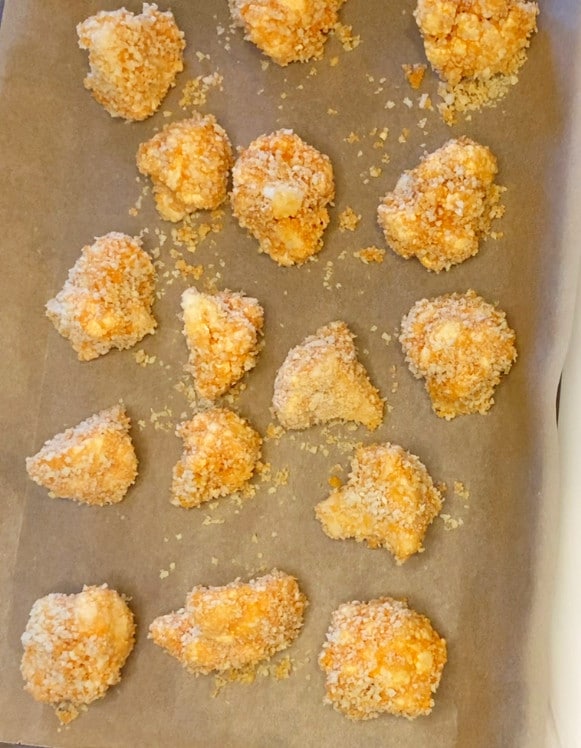 Hot Buffalo Cauliflower Bites on a parchment paper-lined baking sheet ready for to be baked.