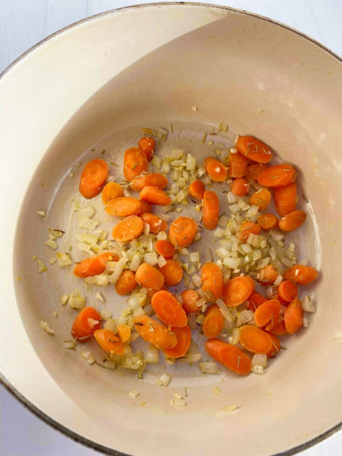 Sauteing onions, garlic, carrots and rosemary in olive oil in a large saucepan