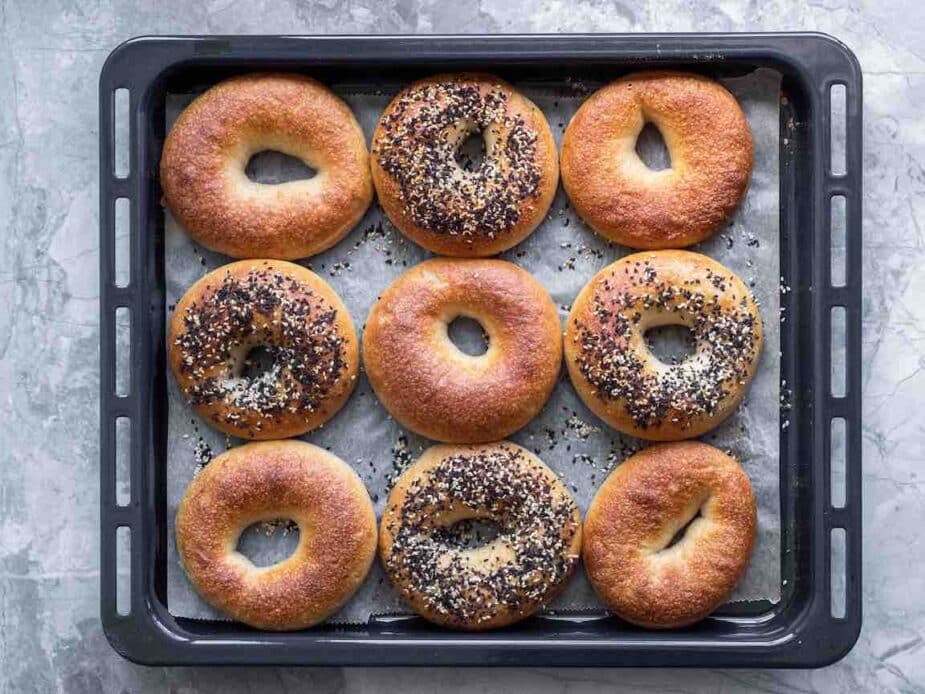 A black tray with 9 bagels on a grey counter