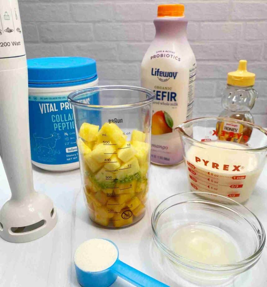 Ingredients to make a mango kefir smoothie sitting on a white counter.