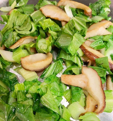 Sauteed baby bok choy with shiitake mushrooms in a skillet