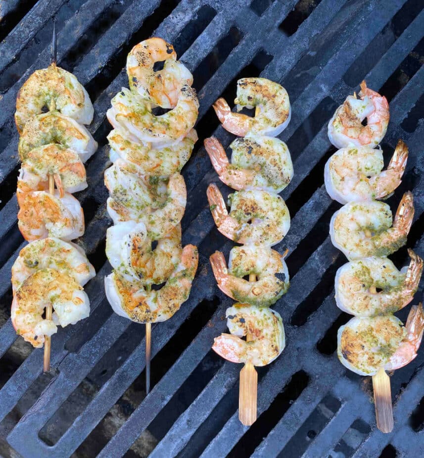 4 wooden skewers of grilled shrimp on grill grates
