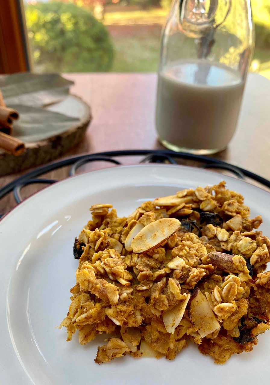 A pumpkin spiced oat bar on a white plate with a glass of milk in the background.