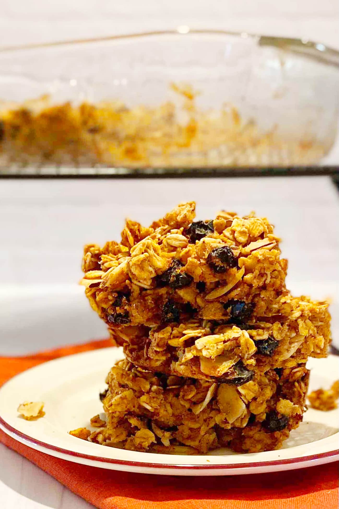 A stack of pumpkin spiced oat bars with a baking pan in the background