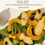 Overhead view of roasted delicata squash and pears on a platter of power greens. Topped with pumpkin seeds and dried cranberries.