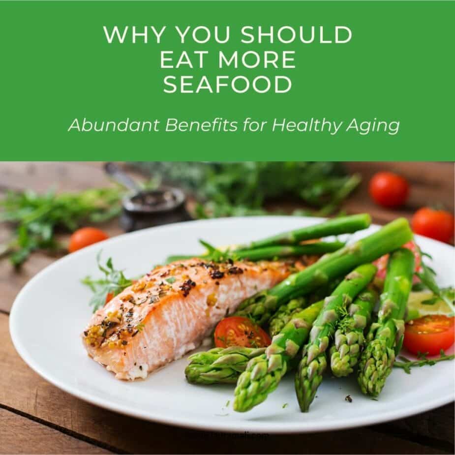 A white plate with baked salmon with asparagus on a wood picnic table.