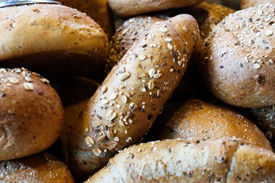 A pile of various loaves of multigrain breads that are topped with oats and seeds.