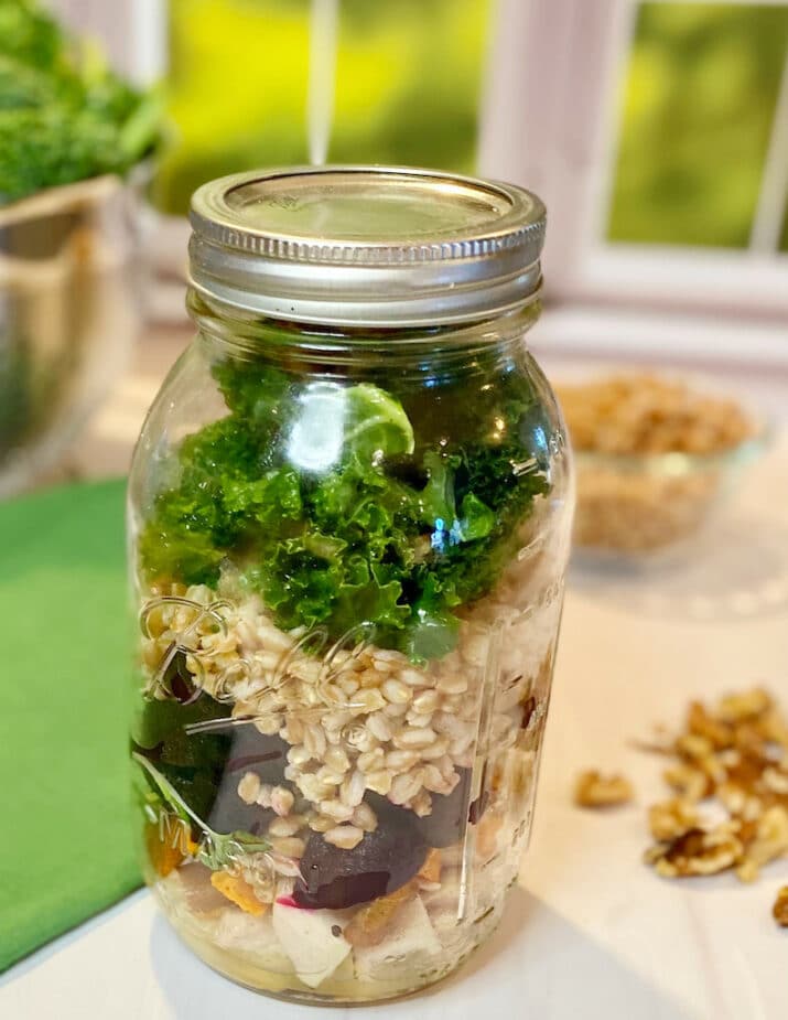 Ancient grains bowl packed in a mason jar sitting on a marble counter top.