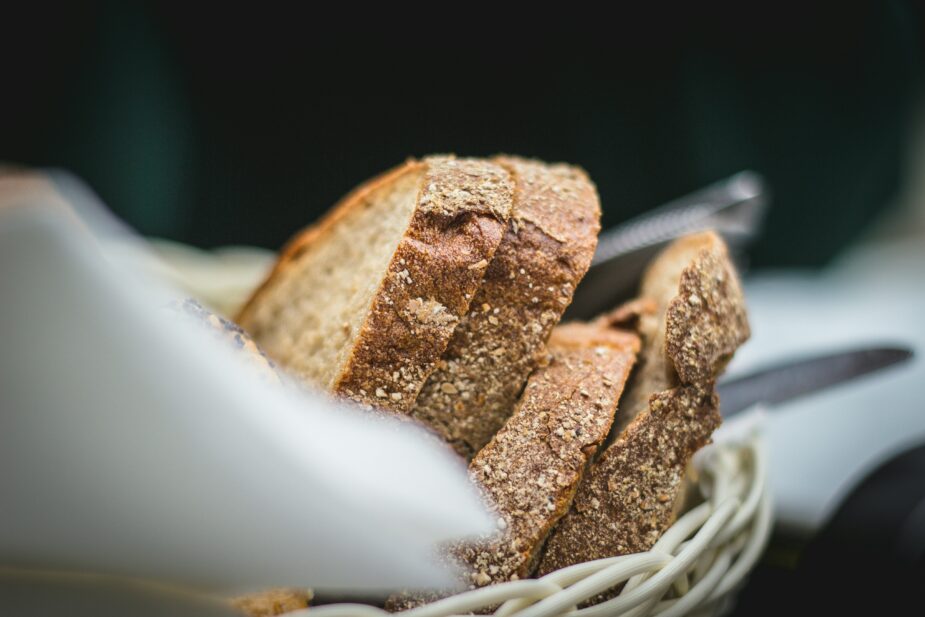 Slices of whole wheat bread in a white wicker basket with a white napkin.