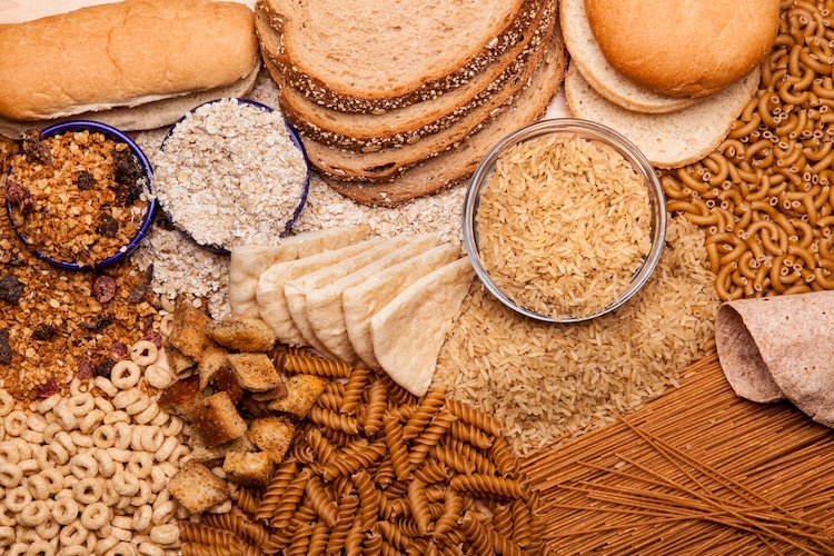 A variety of different types of grains and breads on a wooden cutting board