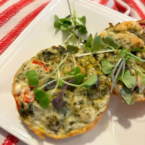 2 cottage cheese and egg muffins on a white plate, garnished with microgreens.