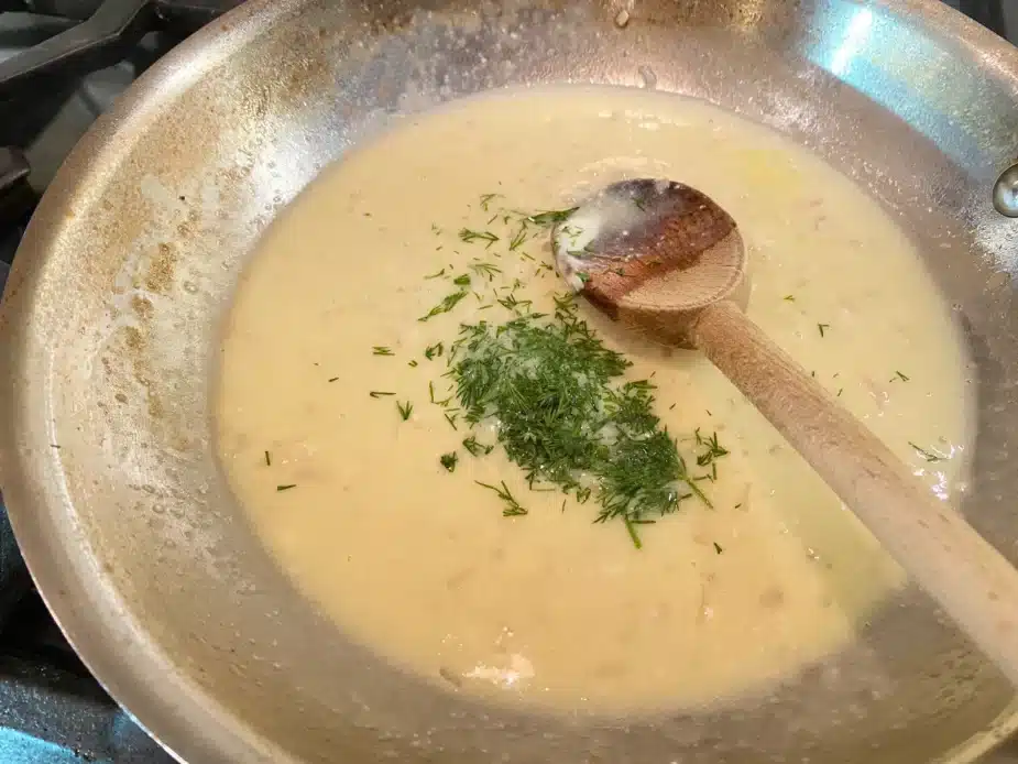 A frying pan with creamy lemon wine sauce to serve over poached fish. 