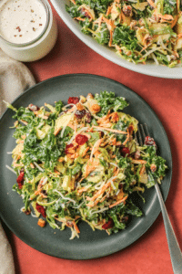 Shaved brussel sprouts and kale salad on a black plate on an orange tablecloths