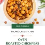 A wooden bowl filled with oven roasted chickpeas on a white counter.